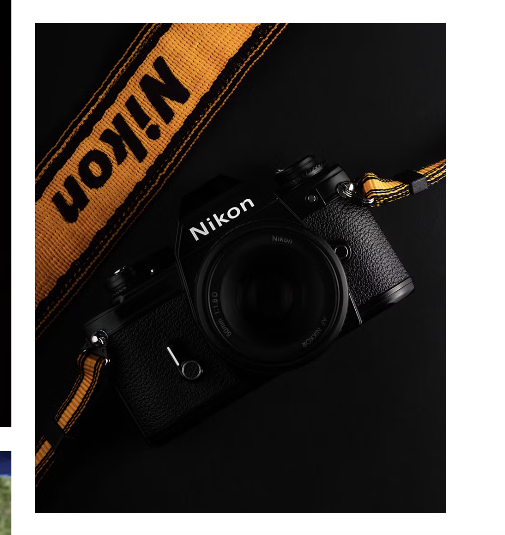 Nikon camera and lens with a yellow Nikon strap on a black background