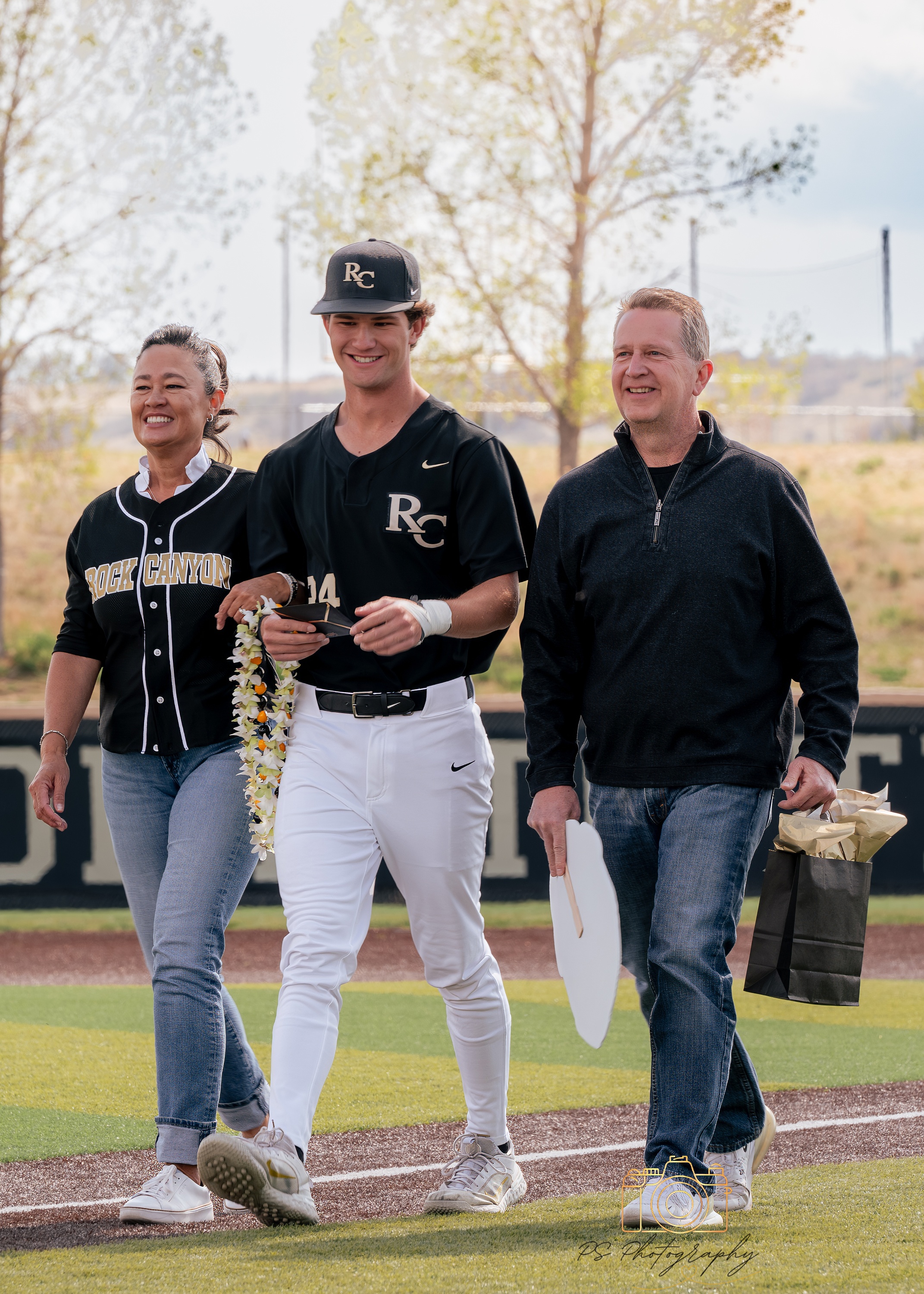 Senior baseball player walking with family during senior night
