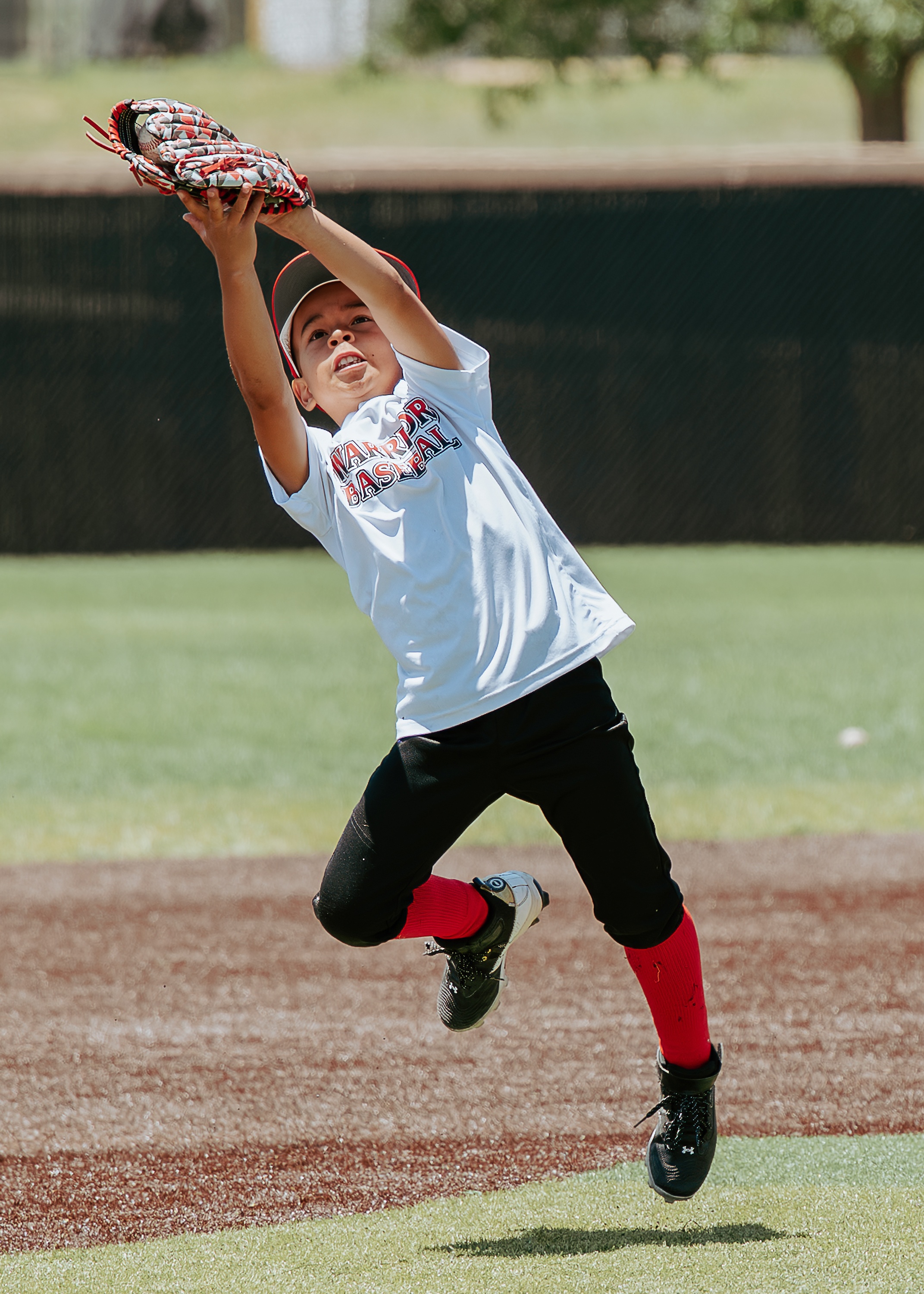 Young baseball player leaping through the air with glove raised for a catch
