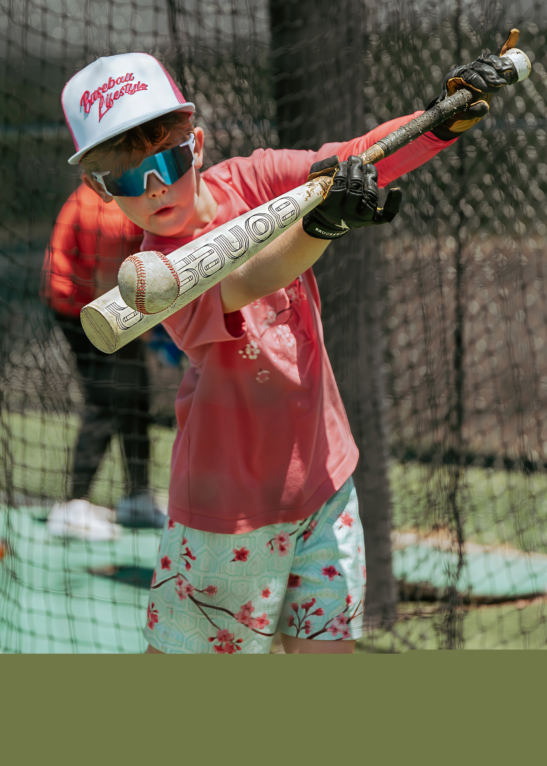 Youth baseball player tracking the ball closely during batting cage practice