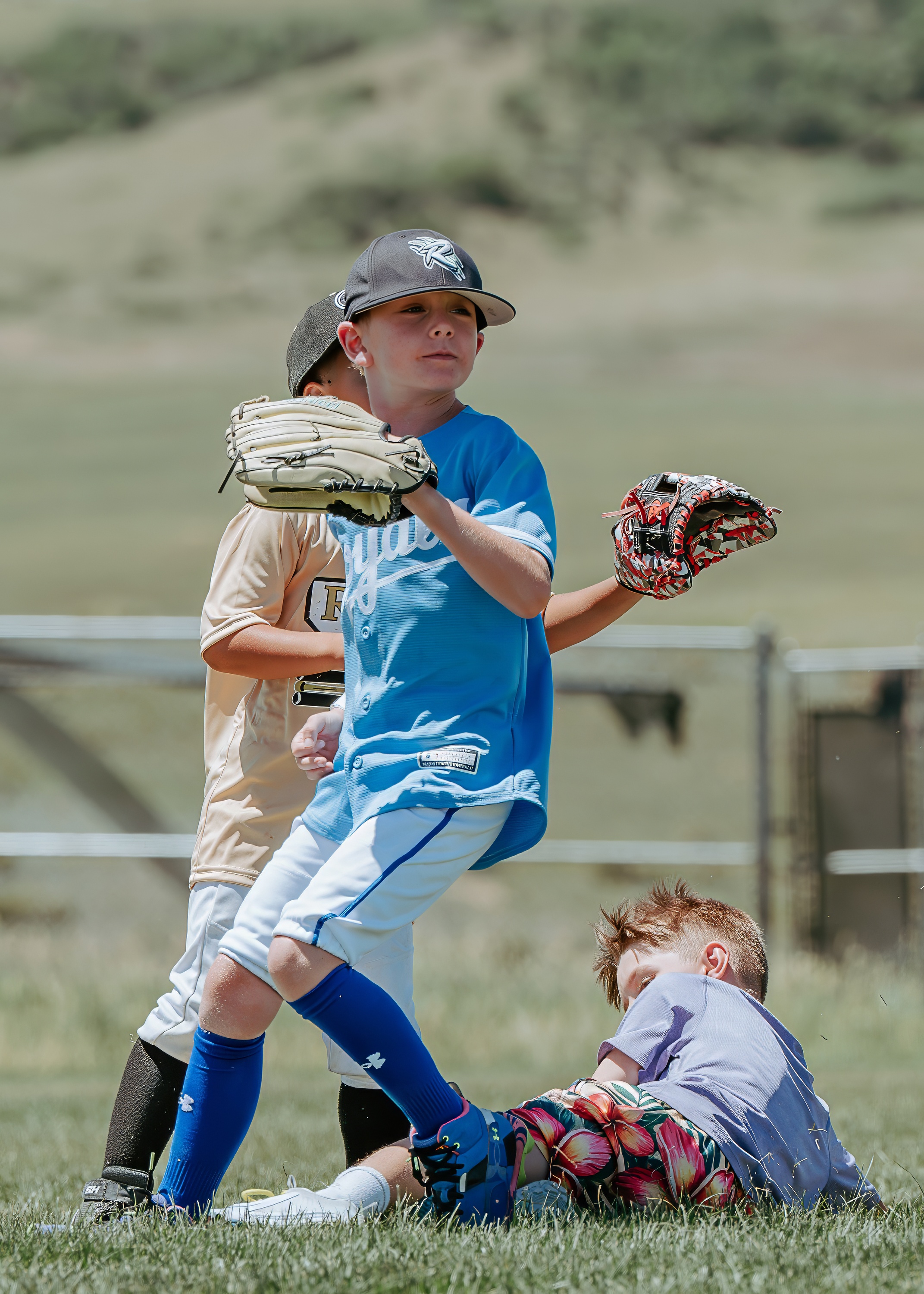Youth baseball players converging on a fielding play in the infield