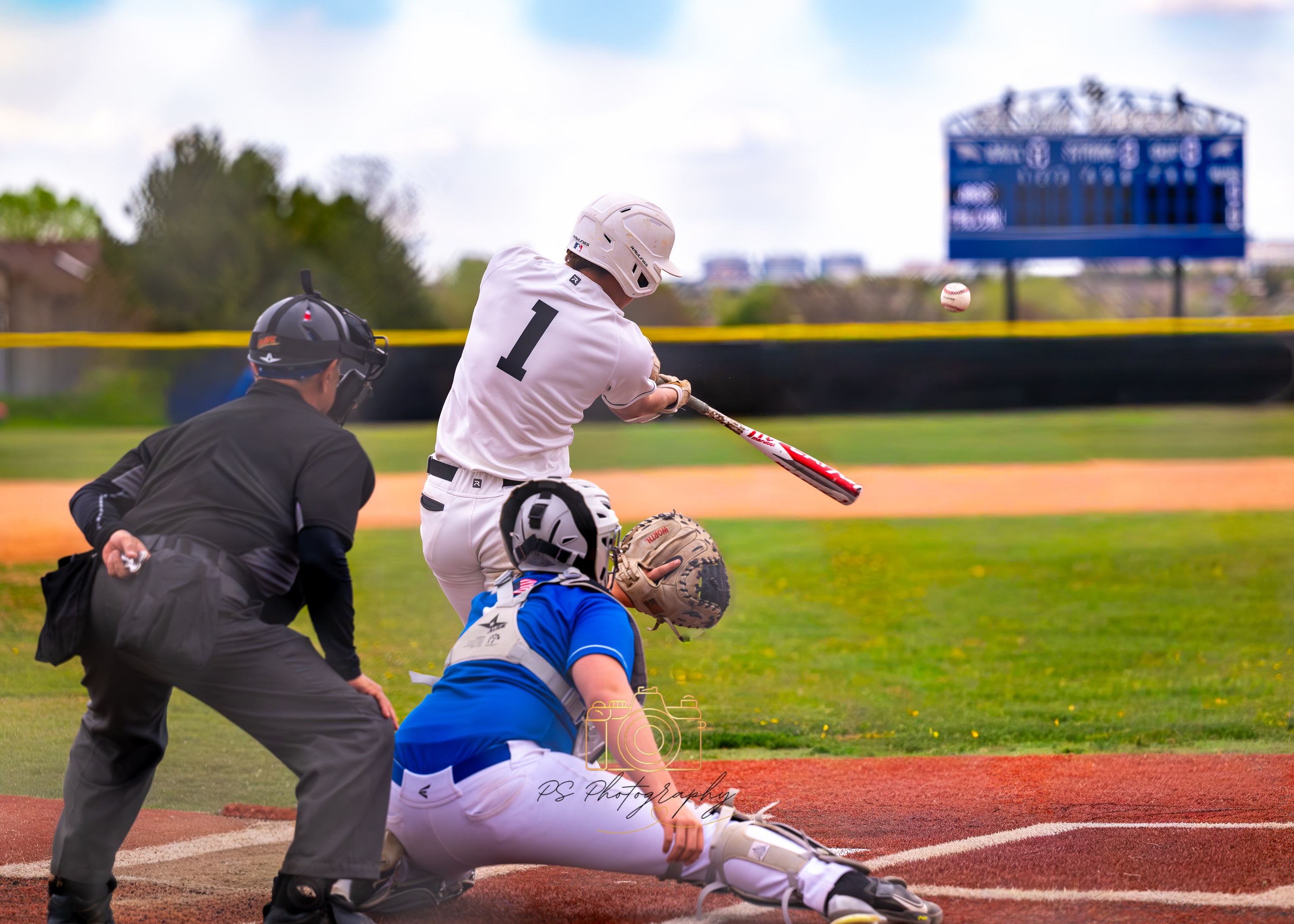 Baseball player making contact with the ball with catcher and umpire behind home plate