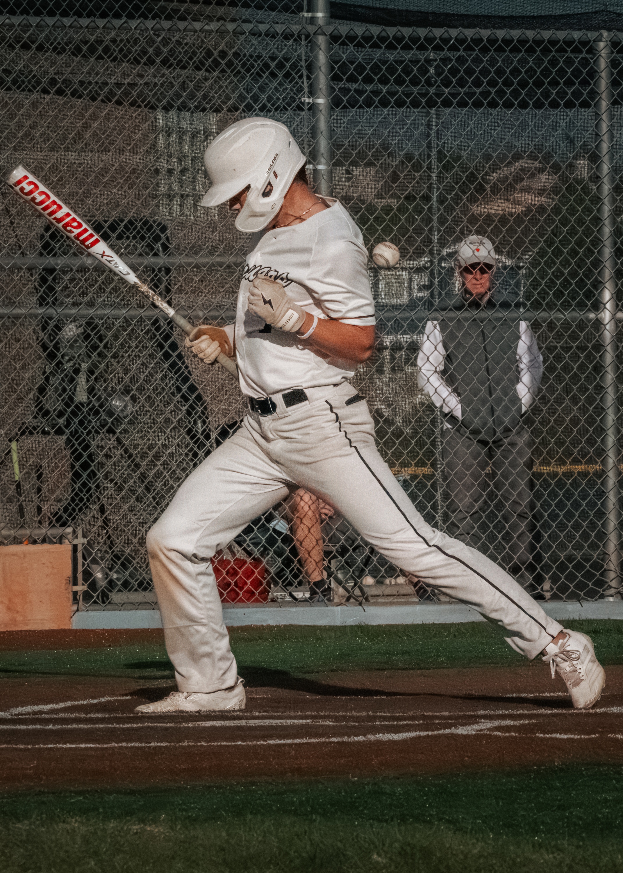 Baseball player swinging at a pitch through the fence