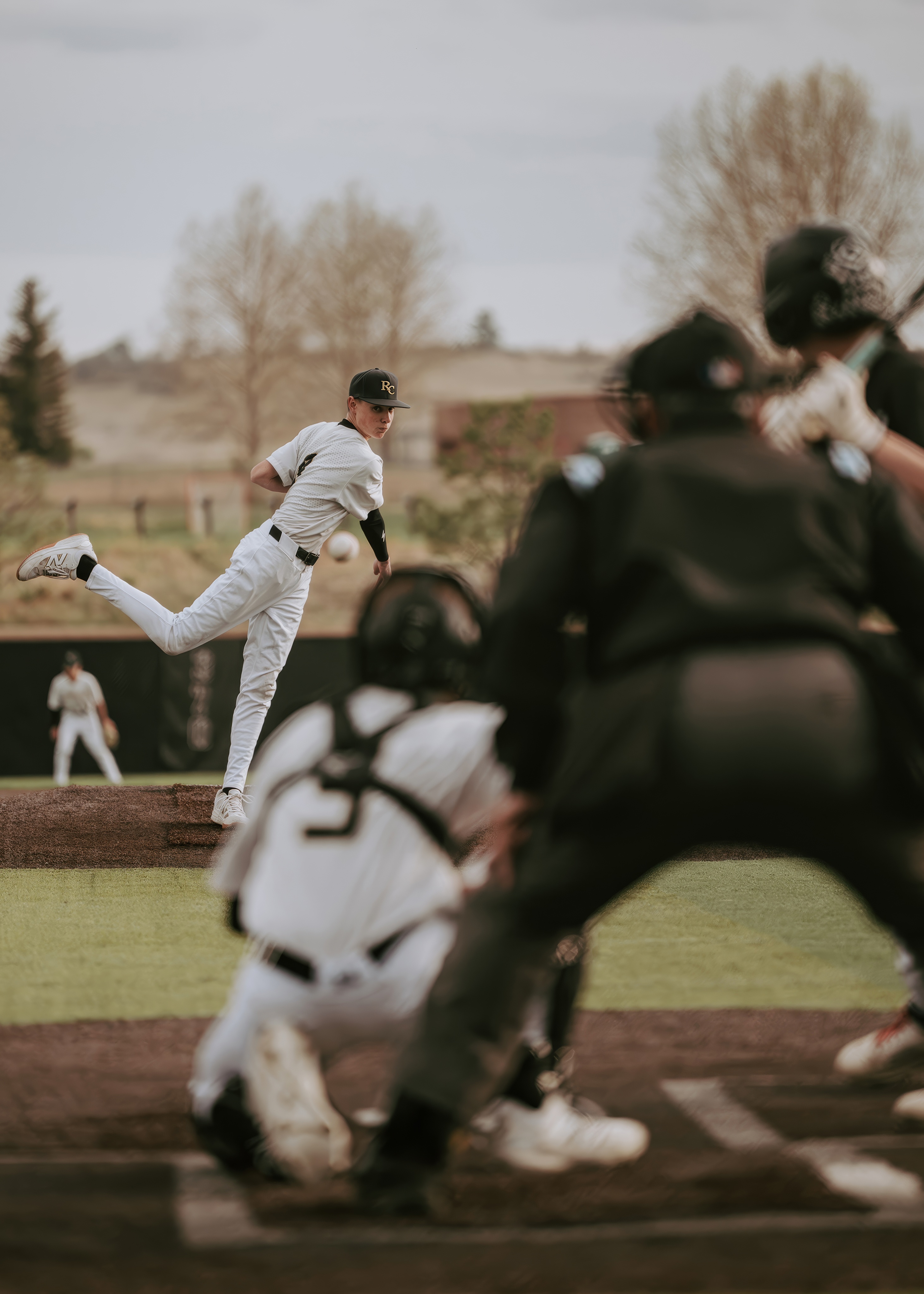Baseball pitcher throwing toward home plate through the catcher and umpire