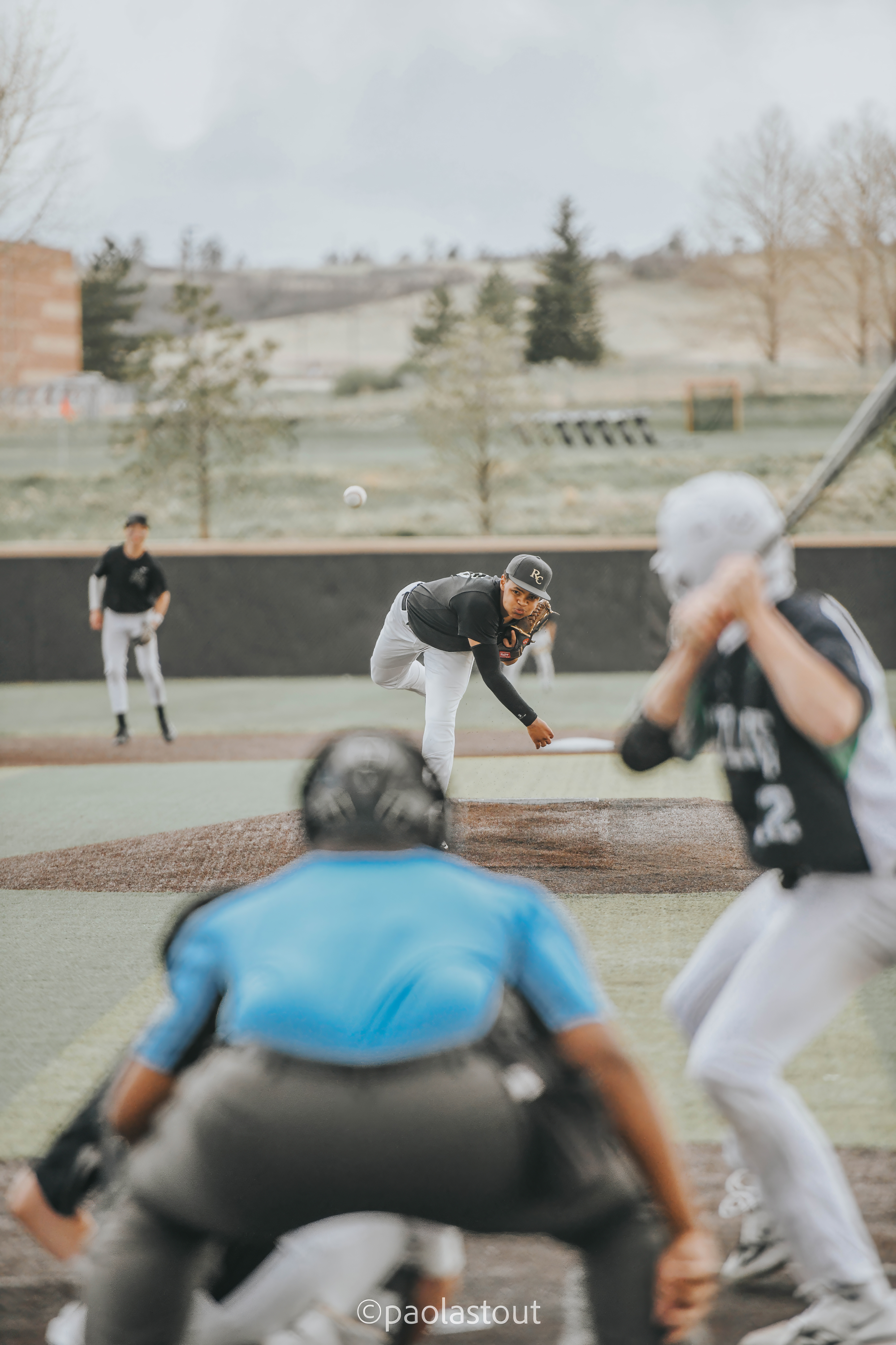 Baseball pitcher throwing toward home plate with batter, catcher, and umpire in the foreground
