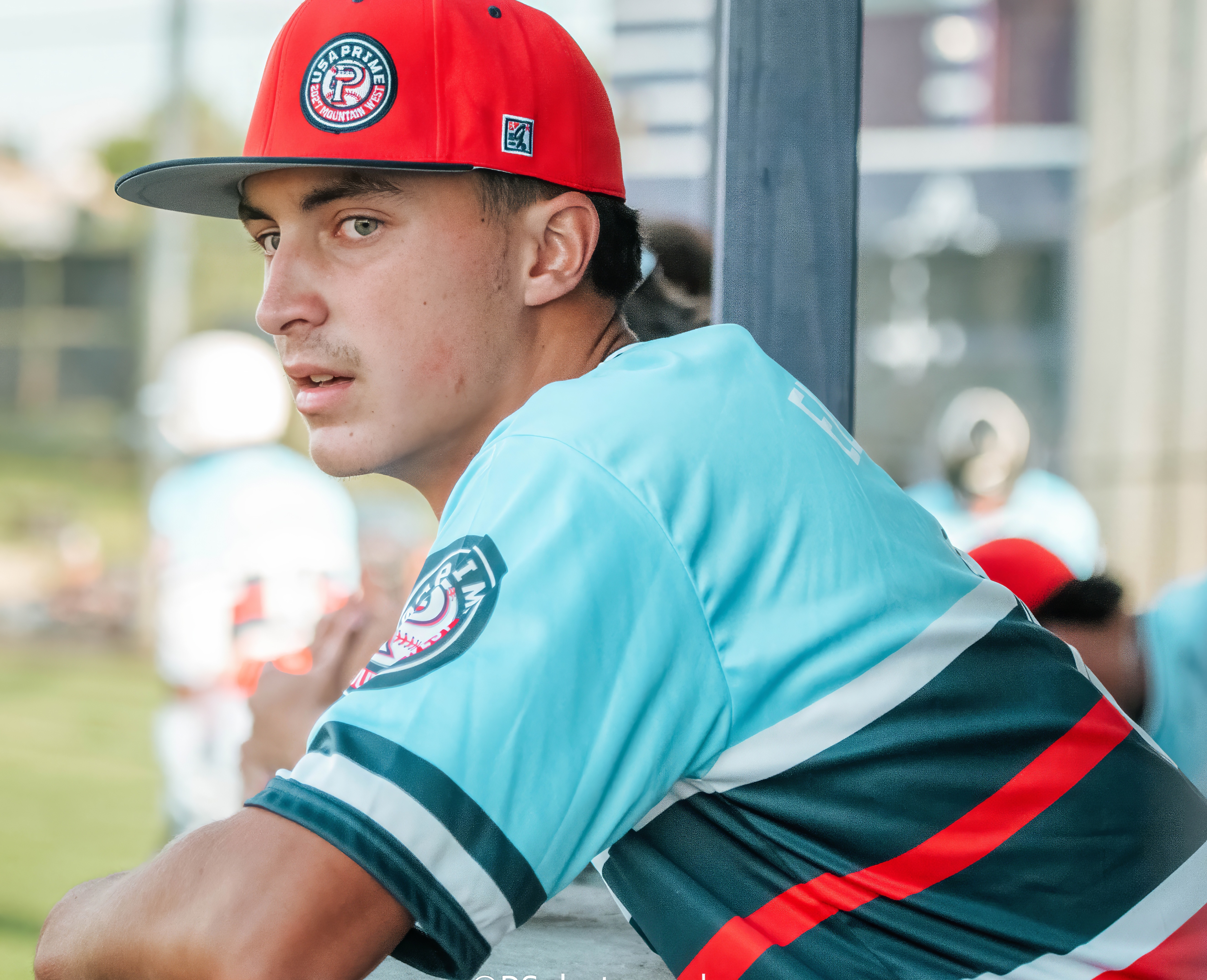 Baseball player leaning on a dugout rail during a game