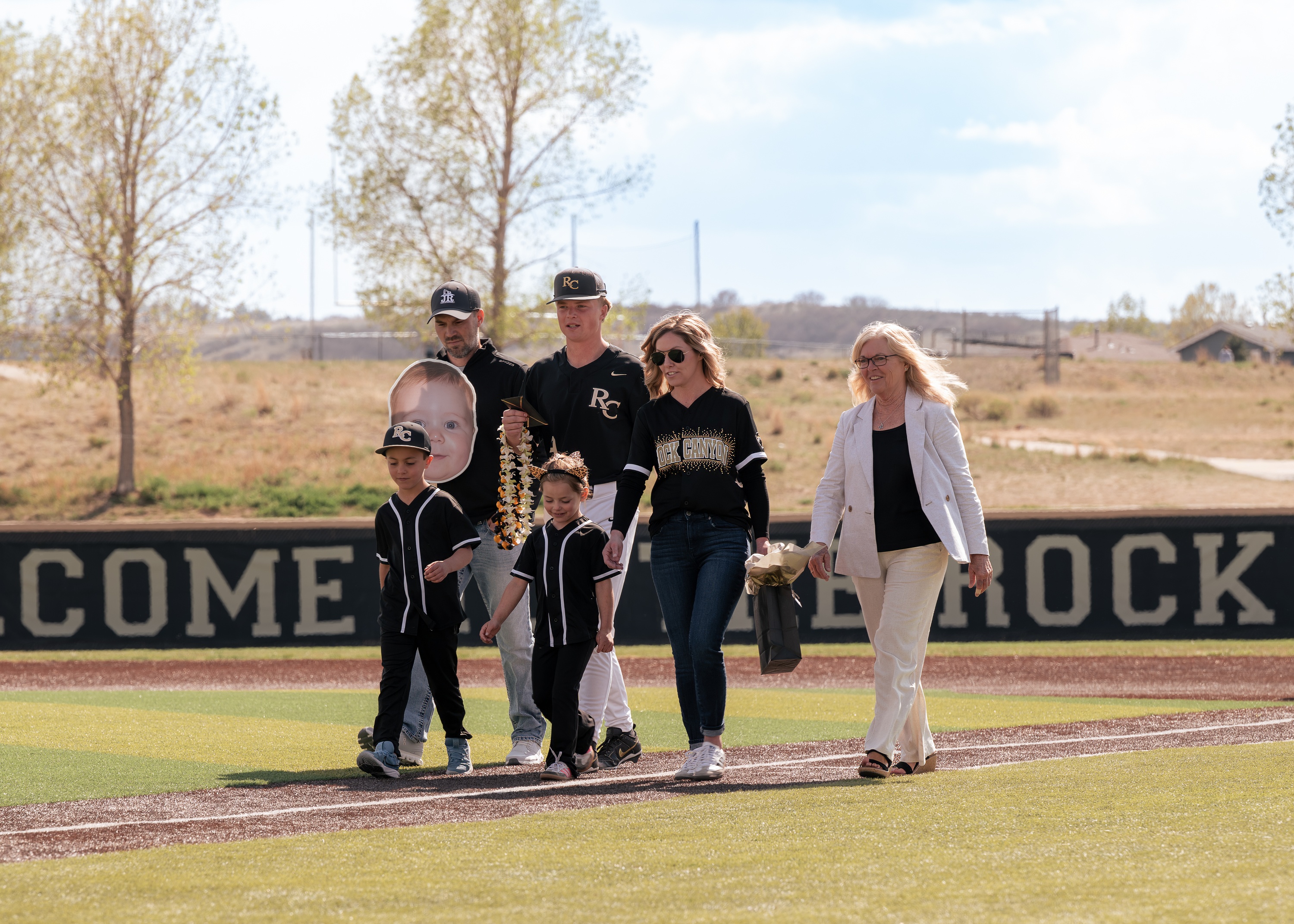 Family walking across the baseball field during senior night