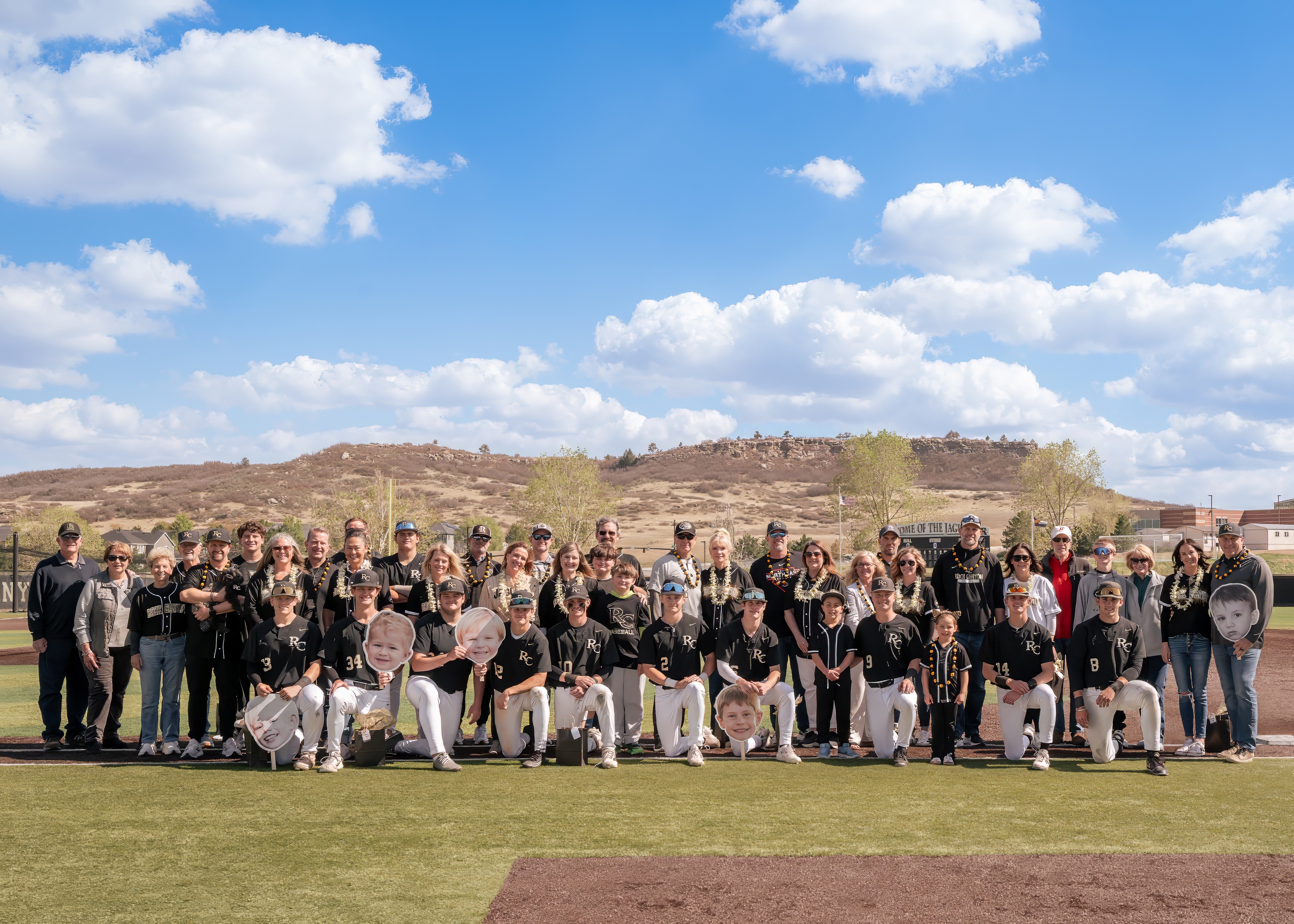 Senior night group photo with baseball players and families on the field