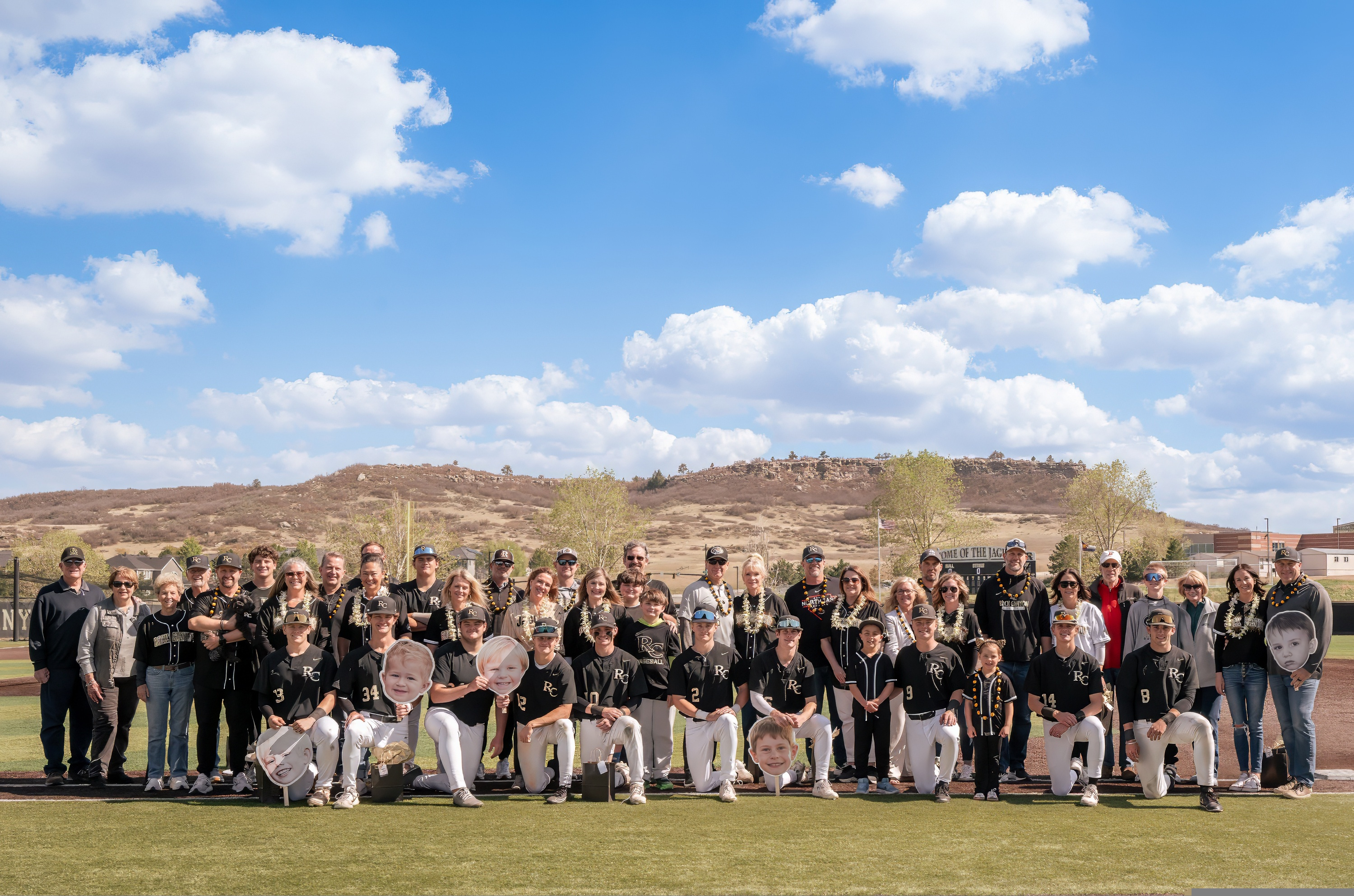 Senior night group photo with baseball players and families on the field