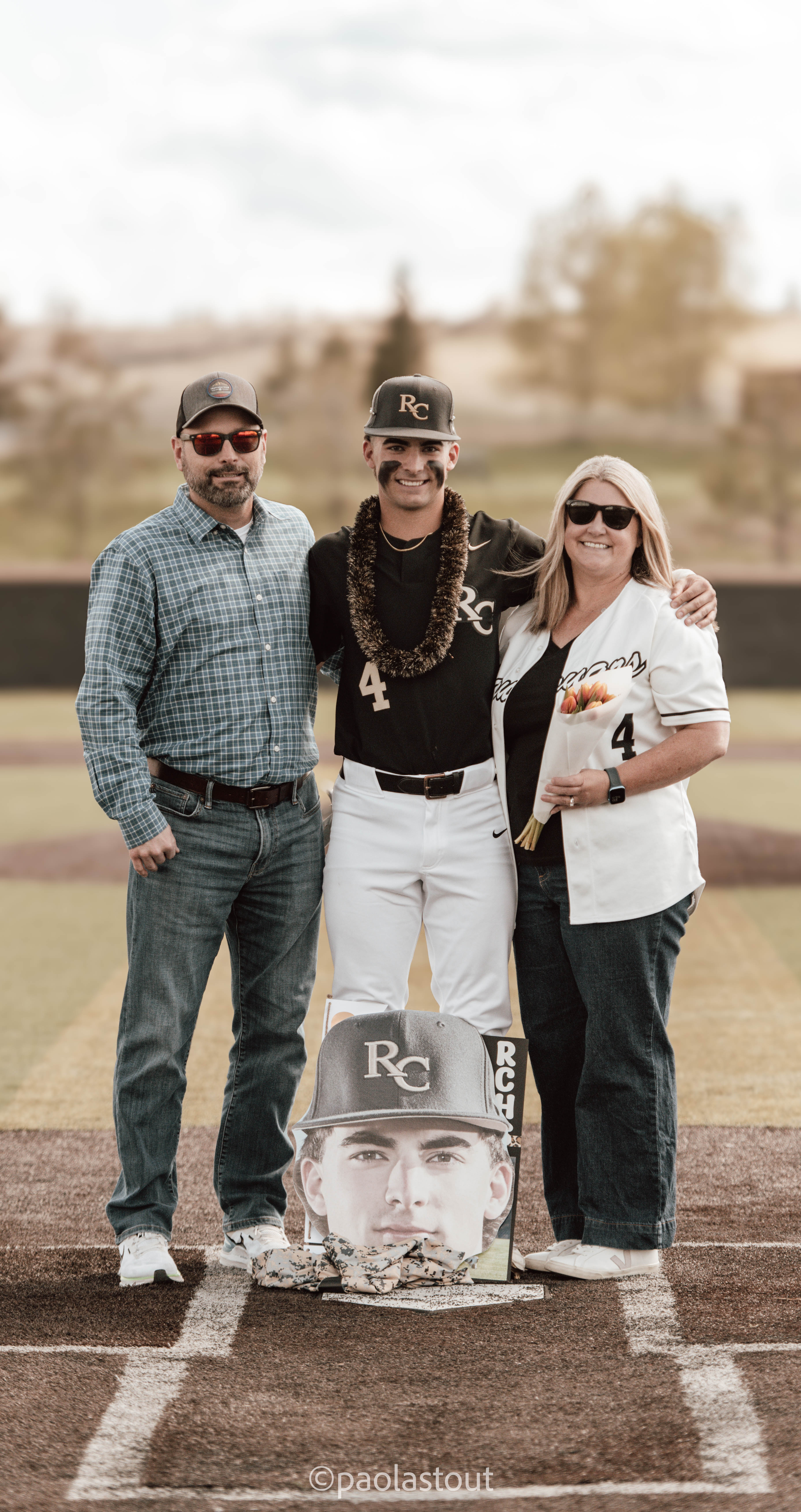 Senior baseball player standing with family on senior night