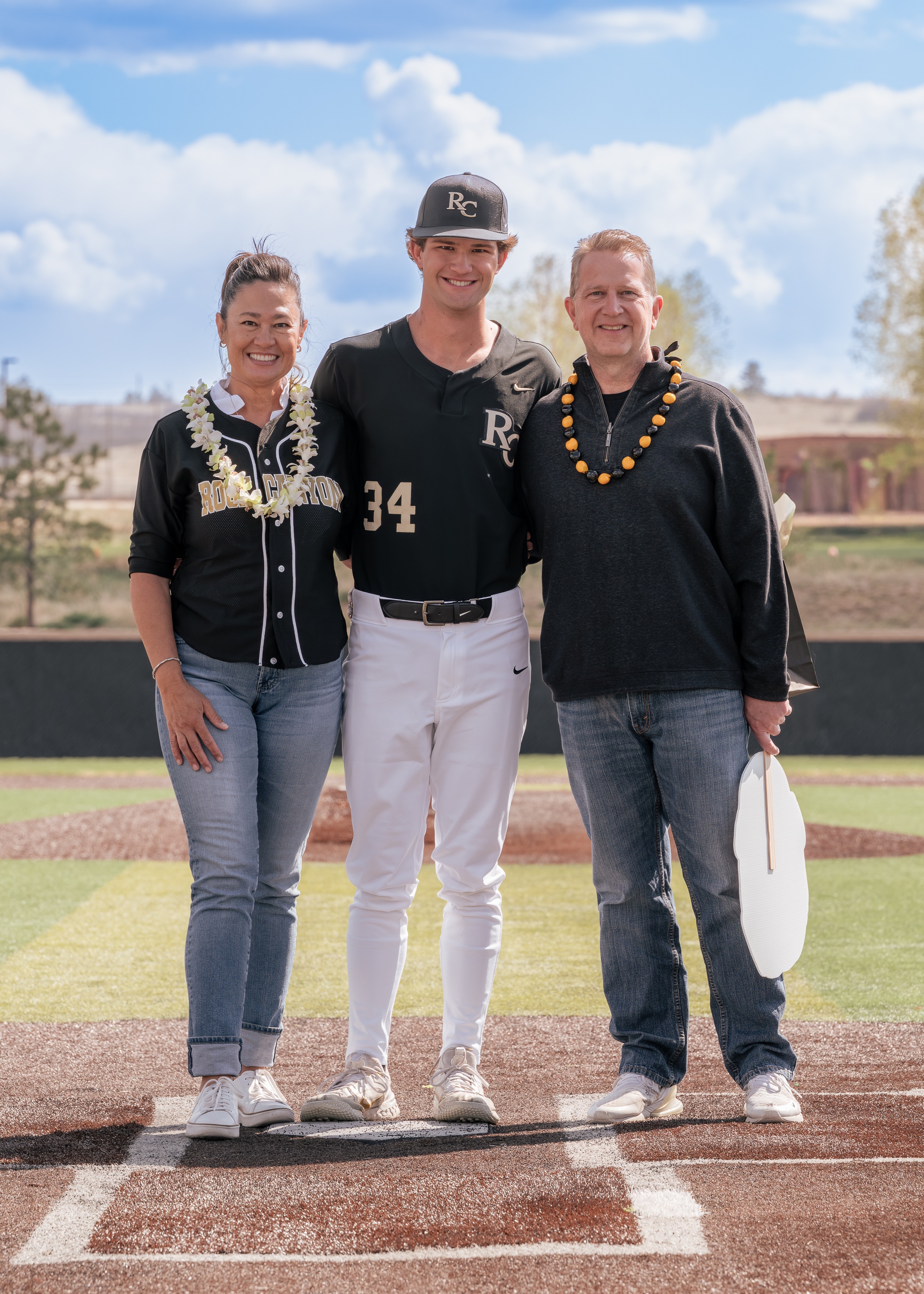 Senior baseball player standing with family on the field