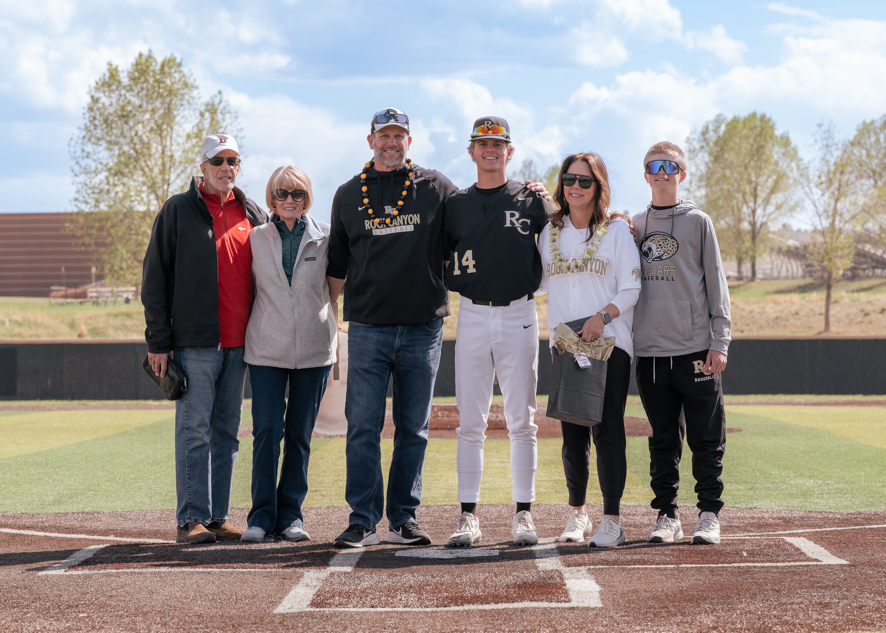 Senior baseball player standing with family on the field